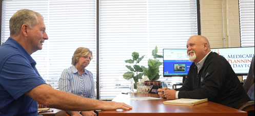 Three people sitting at a desk in an office, discussing.