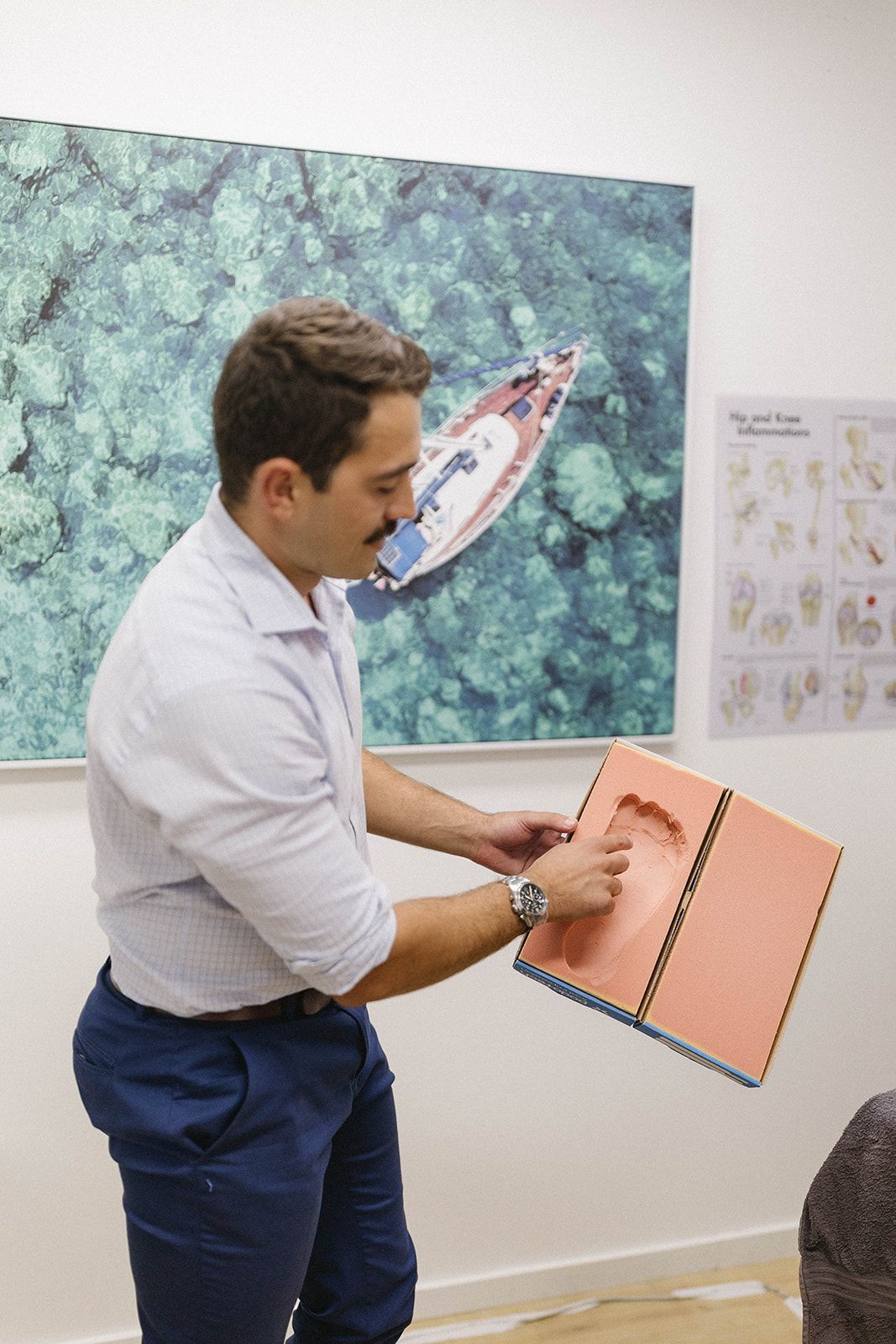 a man is pointing to an imprint of a foot on a red surface   — Biomedical Sports Podiatry in Diamond Beach, NSW