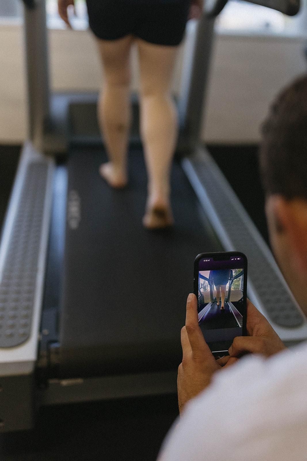 A Man is Taking a Picture of a Woman Walking on a Treadmill — Biomedical Sports Podiatry in Forster, NSW