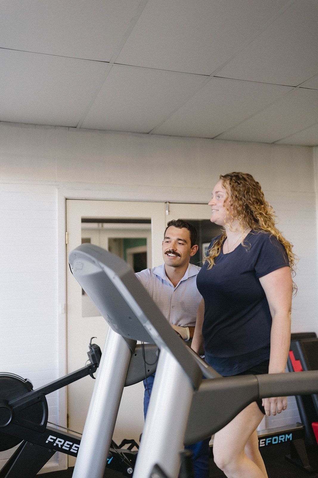 a women waling on a treadmill with a man standing beside her  — Biomedical Sports Podiatry in Forster, NSW