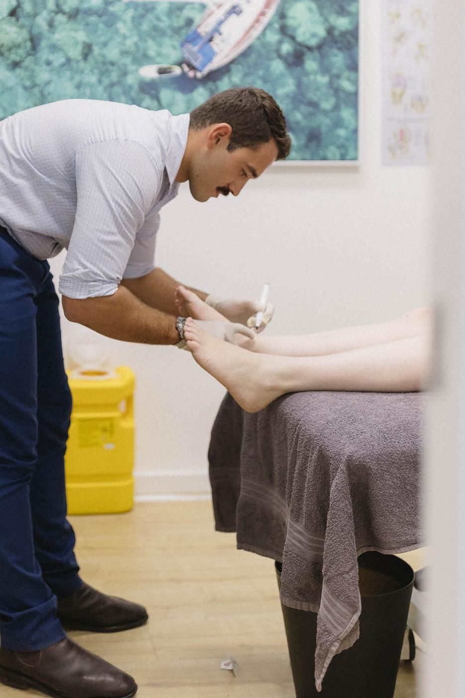A Man is Examining a Patient's Foot in a Hospital — Biomedical Sports Podiatry in Forster, NSW
