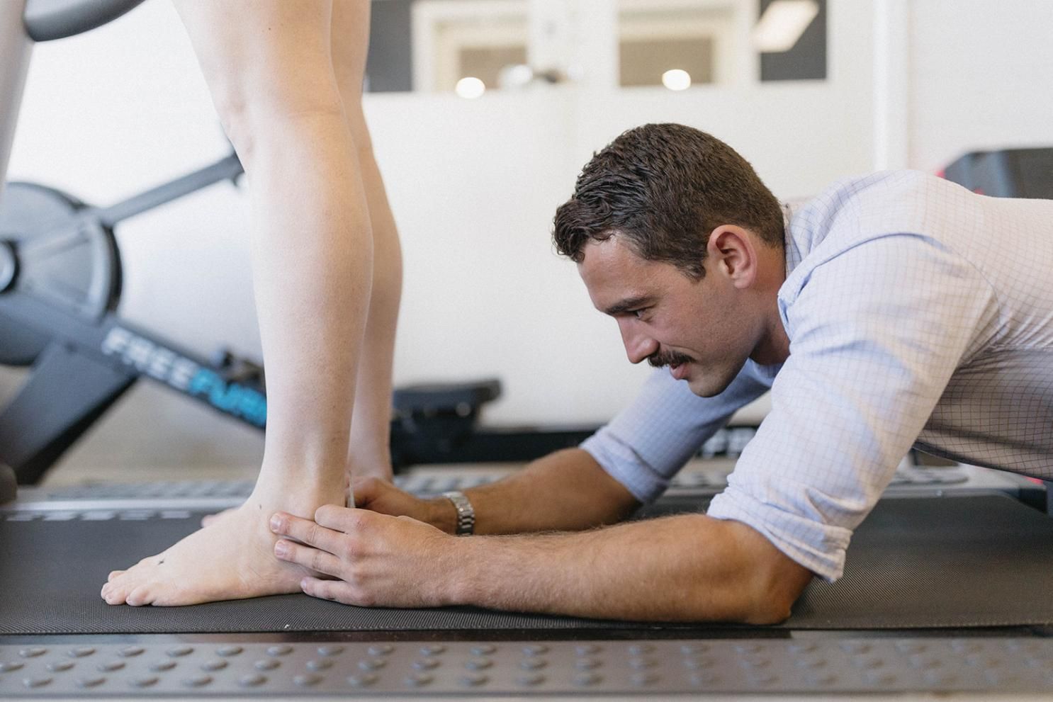 A Man is Examining a Woman's Foot on a Treadmill — Biomedical Sports Podiatry in Forster, NSW