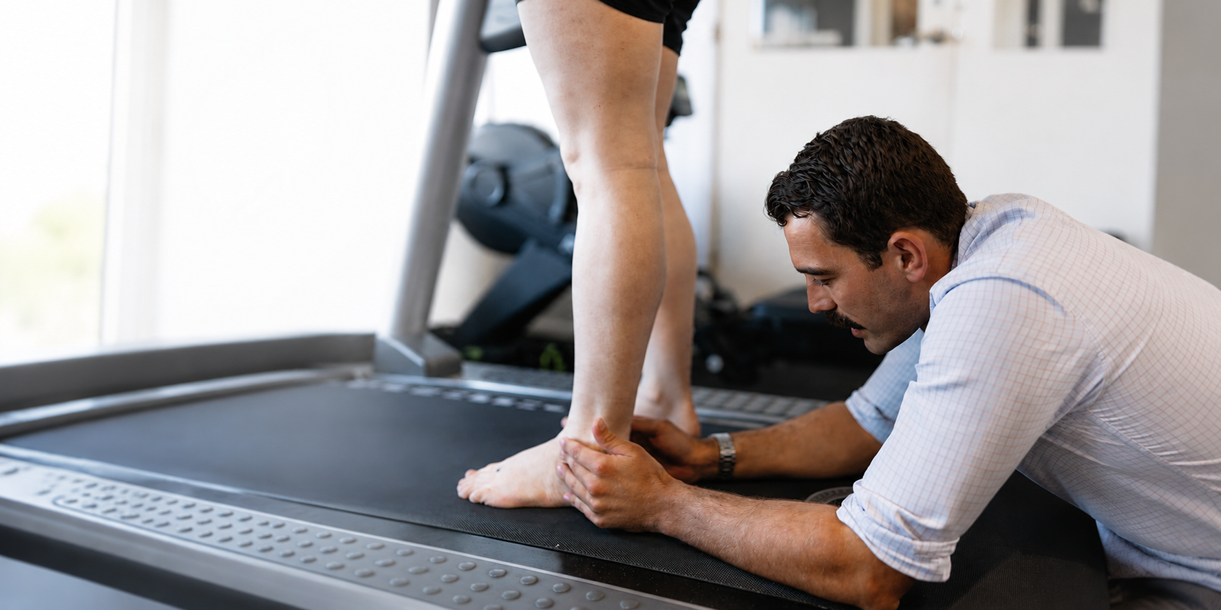 Trainer stretching a person’s foot on a treadmill in a gym — Biomedical Sports Podiatry in Forster, NSW