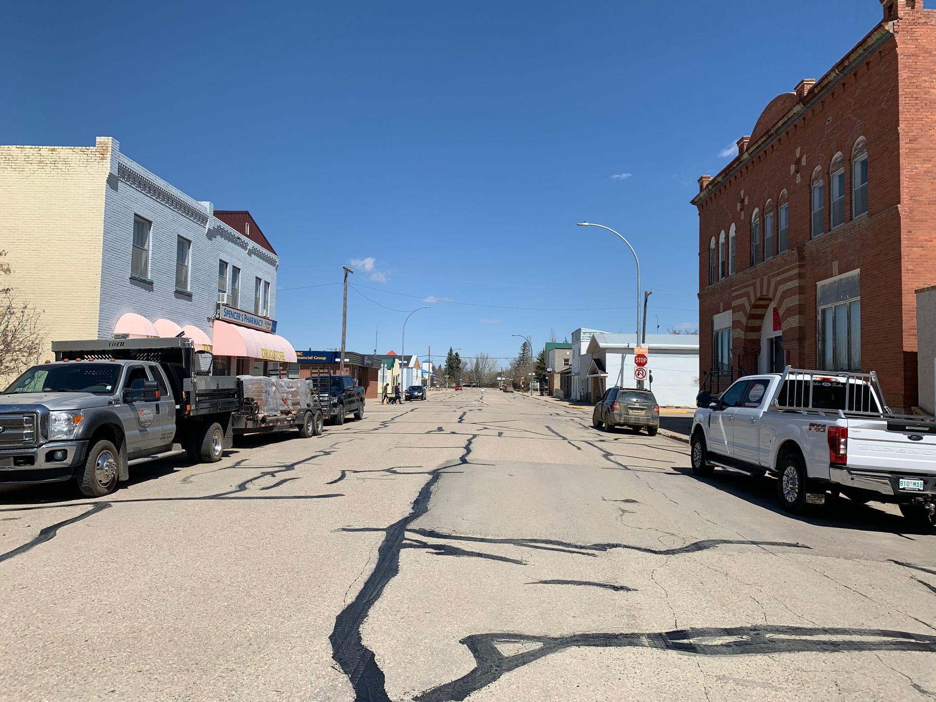 Woman in straw hat smiles, holding wine glass near a lake.