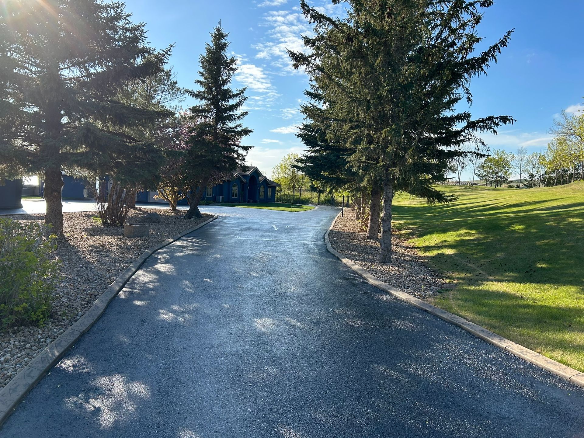 Woman in straw hat smiles, holding wine glass near a lake.