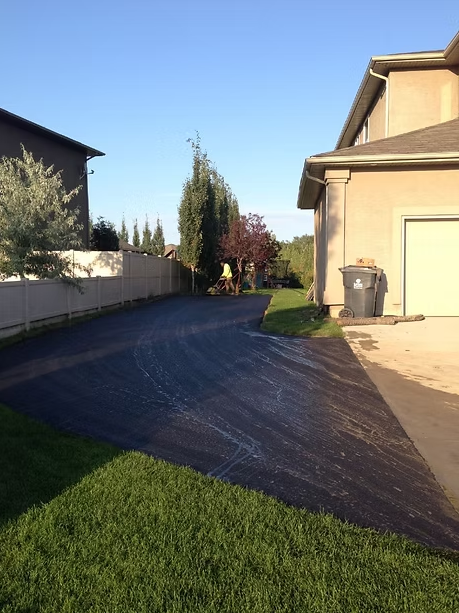 Woman in straw hat smiles, holding wine glass near a lake.