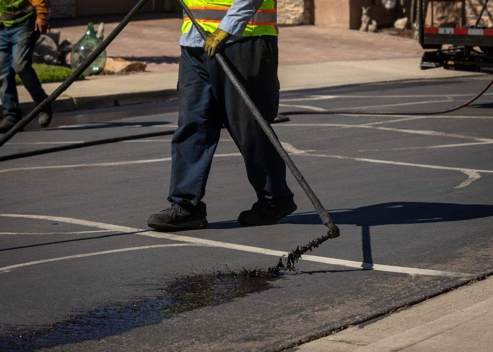 Woman in straw hat smiles, holding wine glass near a lake.