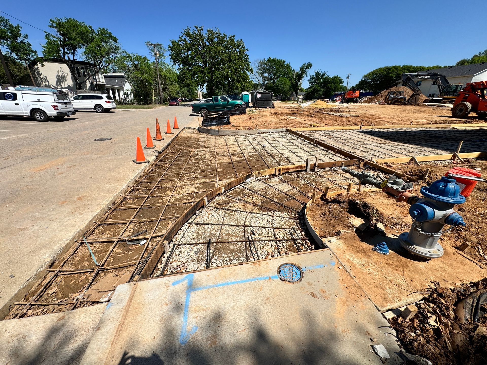 Construction site with exposed rebar, concrete forms, and equipment. A fire hydrant sits nearby.