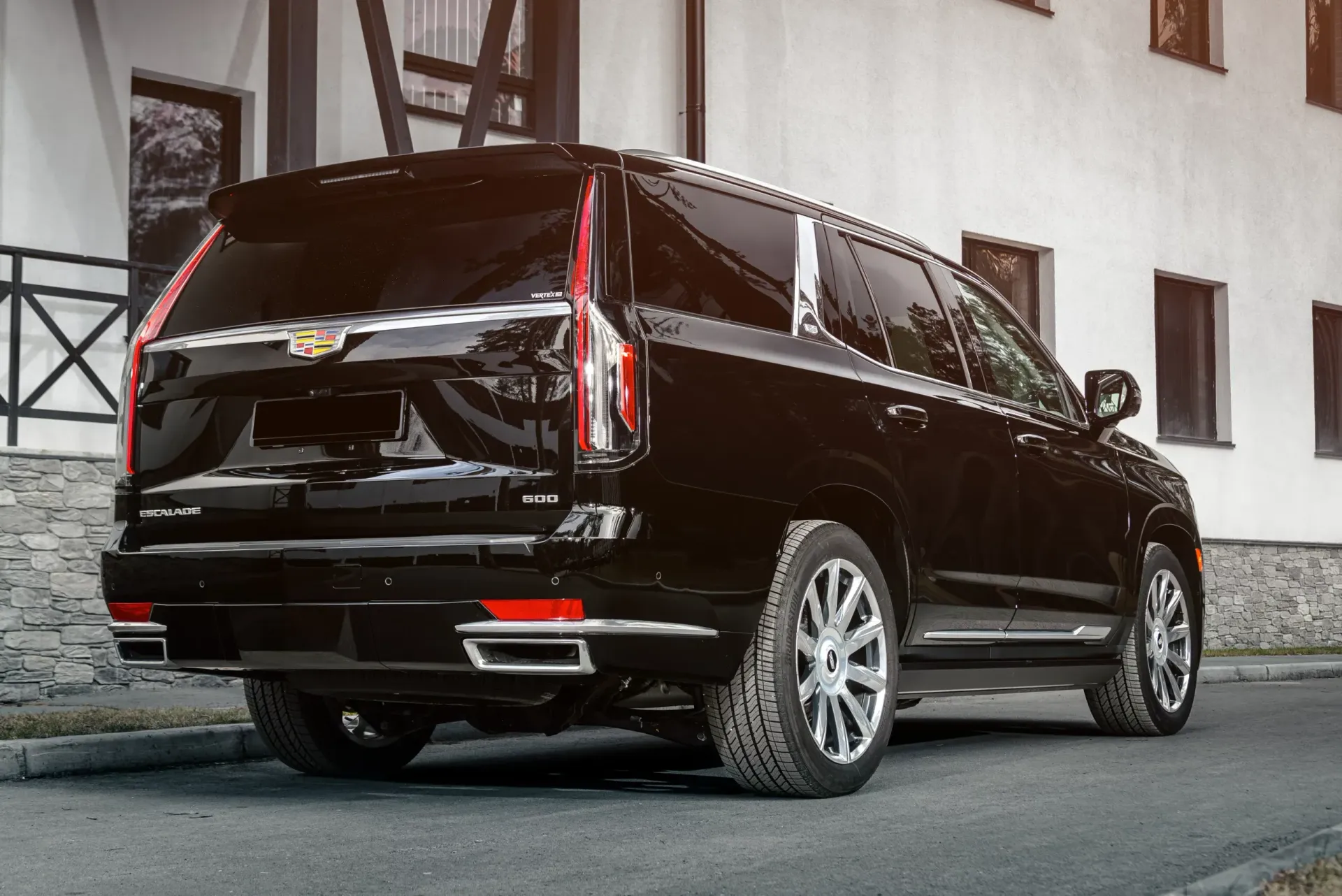 A black cadillac escalade is parked in front of a building.