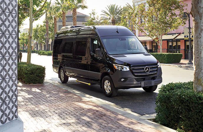 A black mercedes sprinter van is parked on the side of the road.