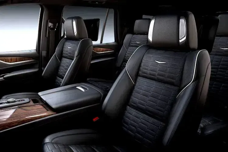 The interior of a cadillac escalade with black leather seats and wooden trim.