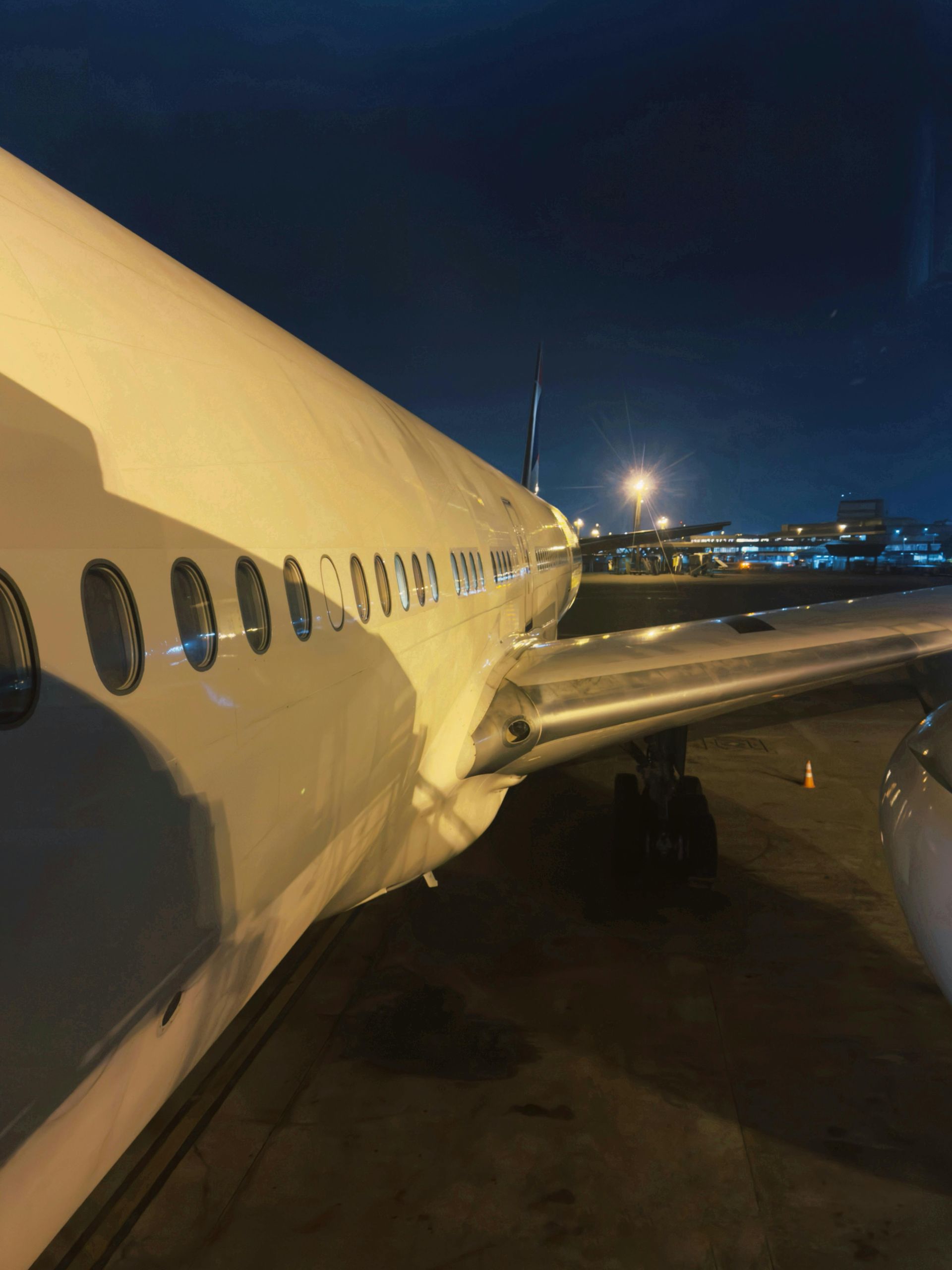 A white airplane is parked on a runway at night