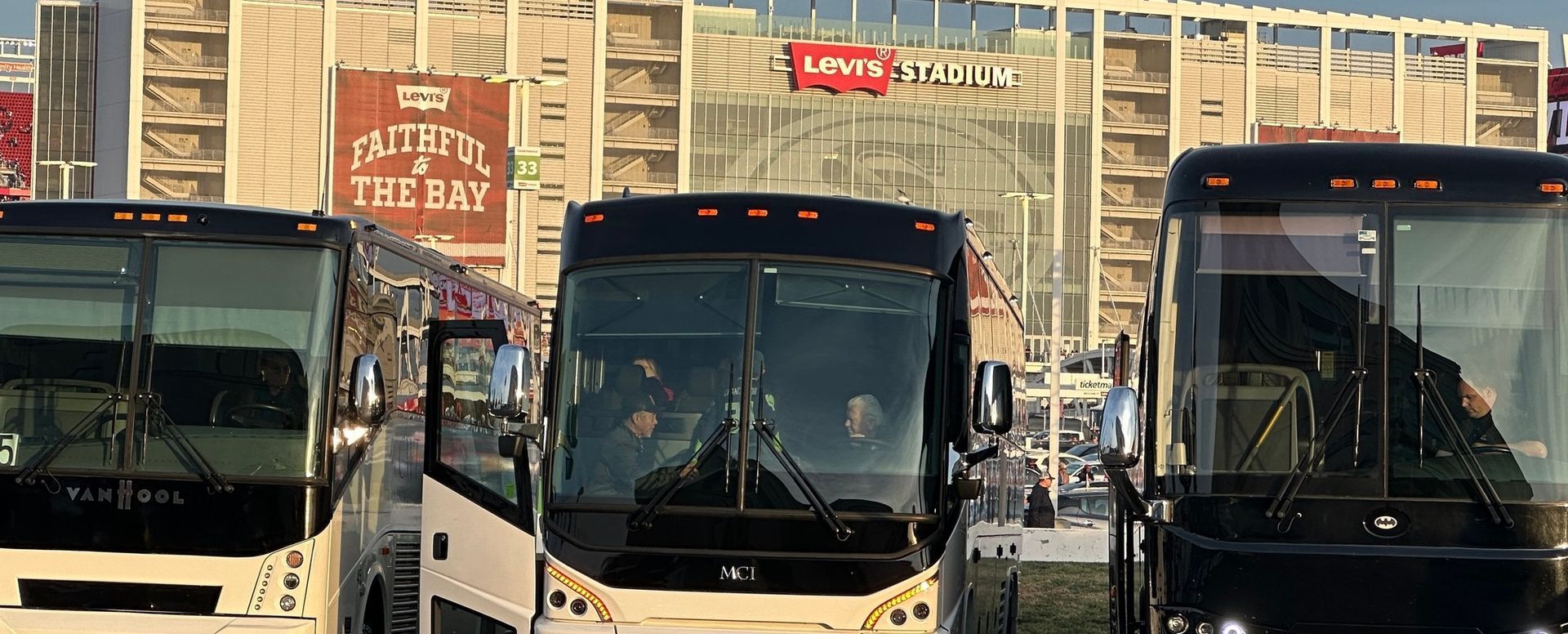 A group of buses are parked in front of a building.