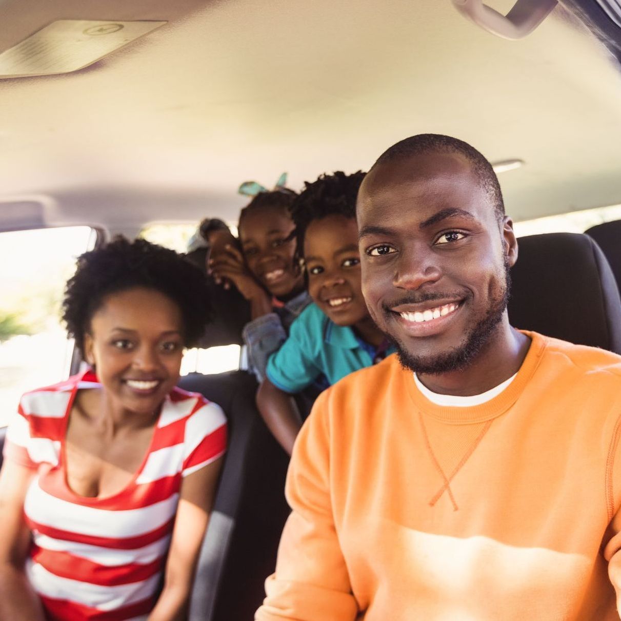 A group of people are sitting in a car and smiling for the camera