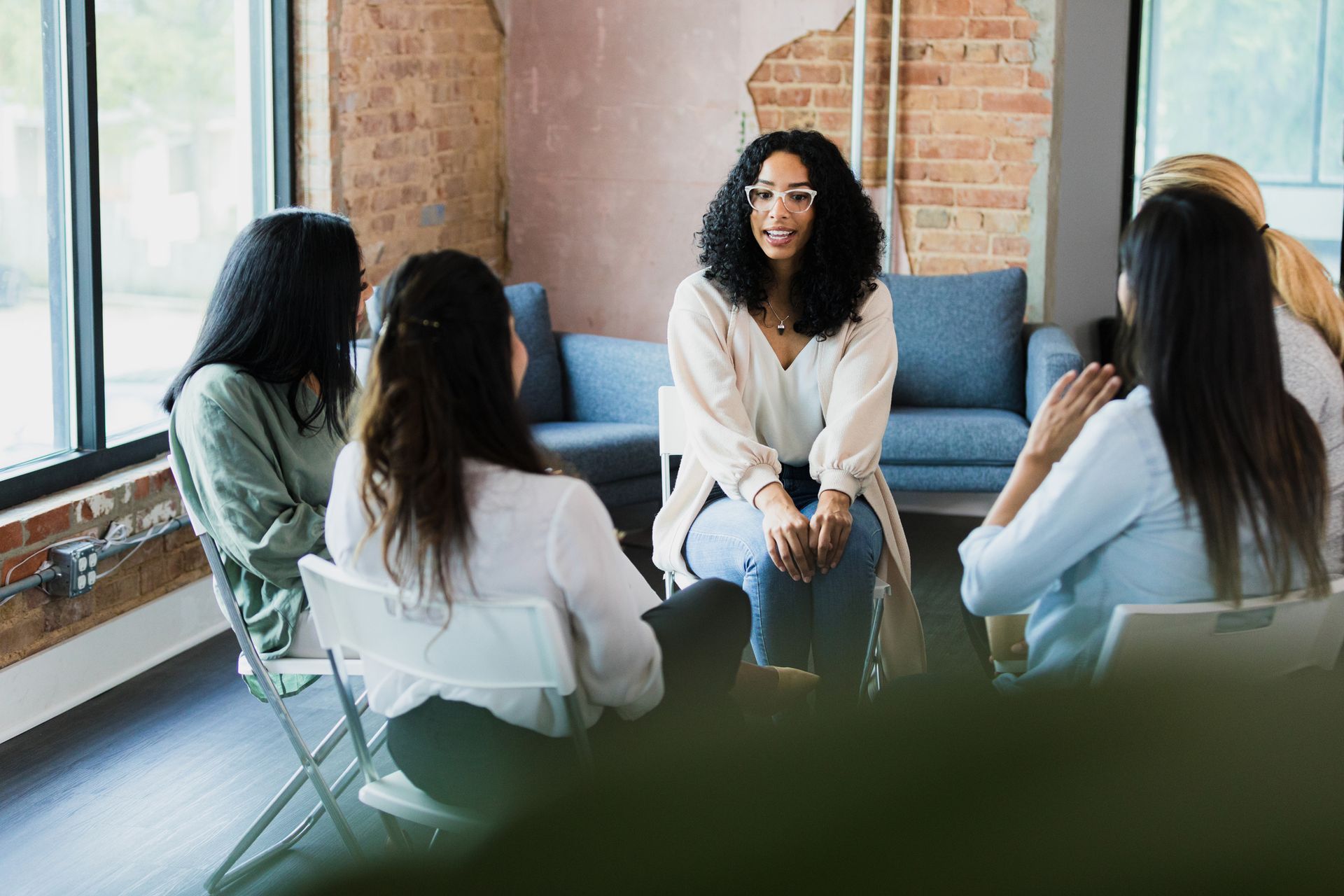 A group of women are sitting in a circle talking to each other.