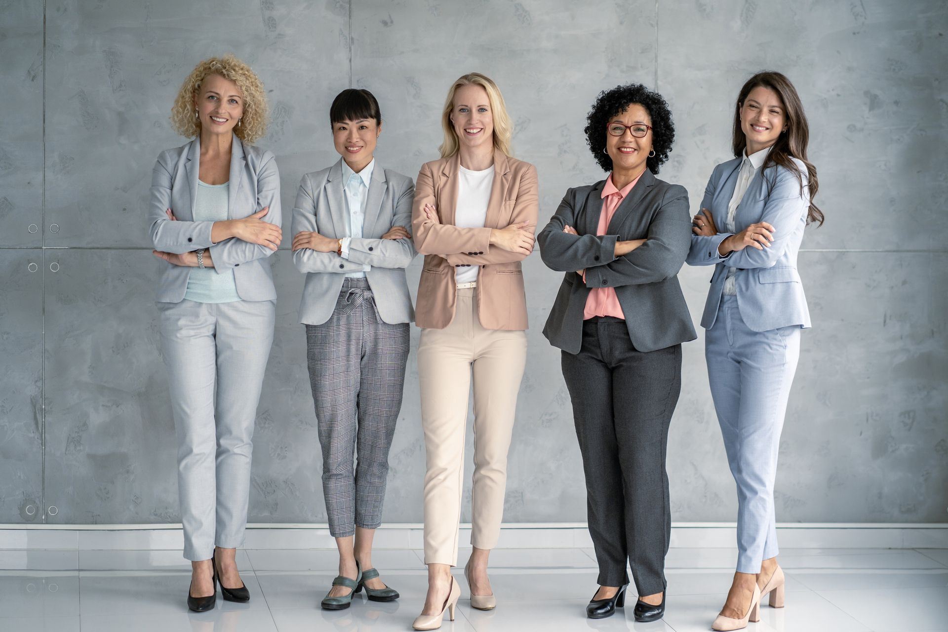 A group of women are standing next to each other with their arms crossed.