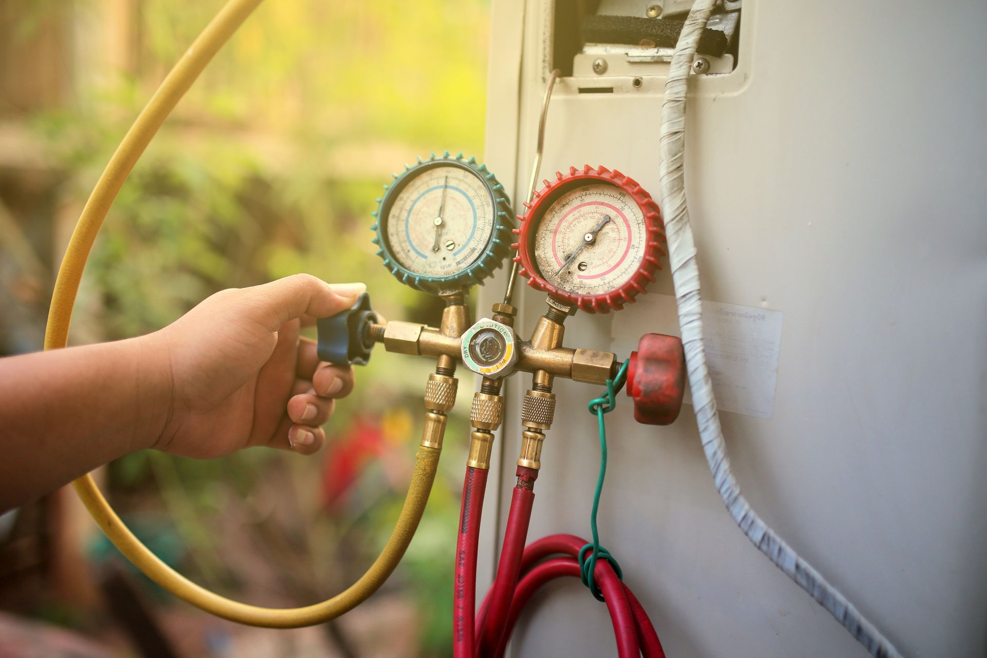 Hand adjusting HVAC manifold gauges on AC unit.