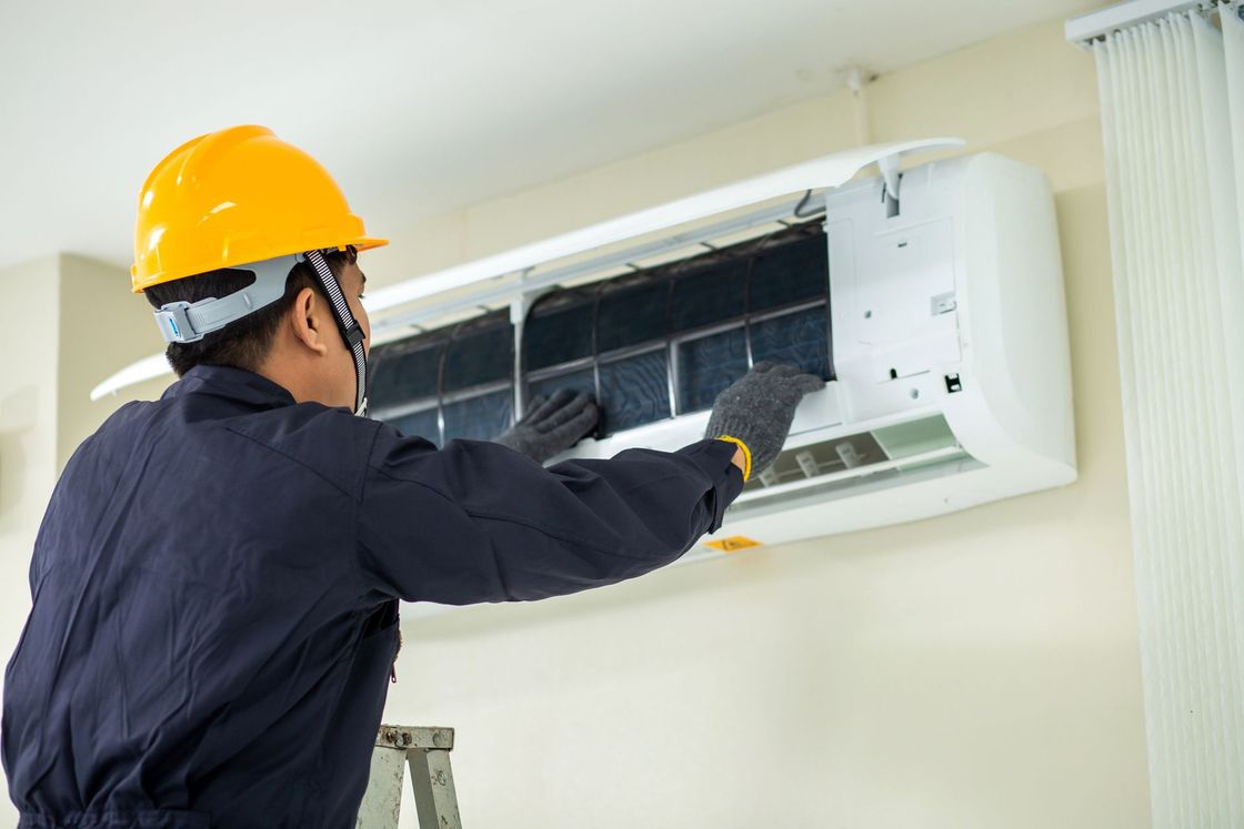 A technician repairing an air conditioner at a residential property.