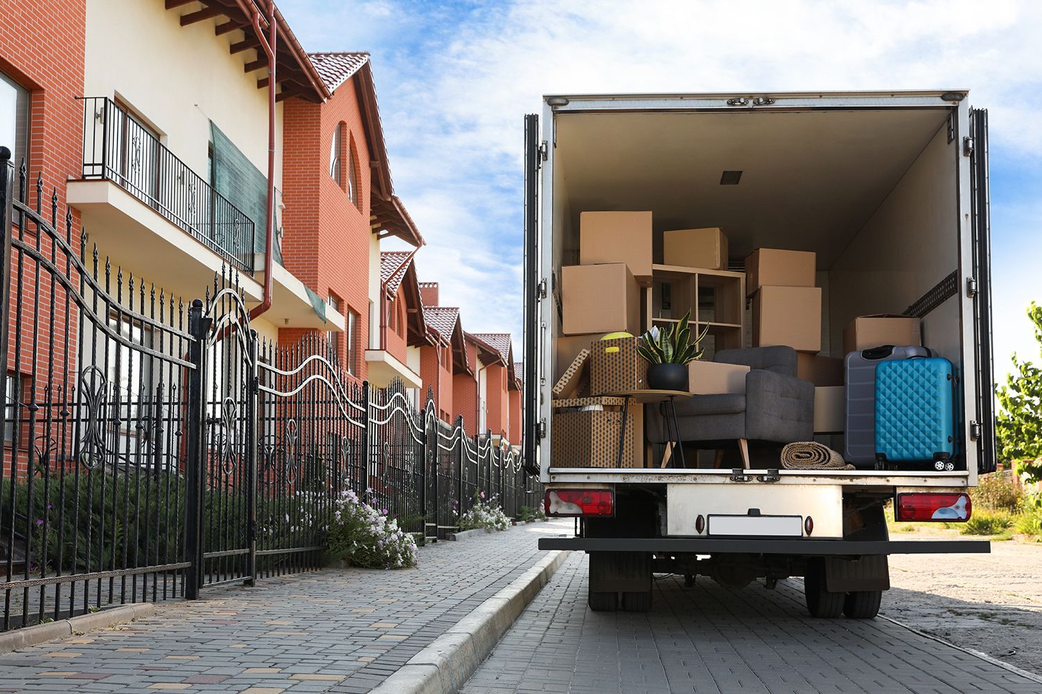 A van full of moving boxes and furniture parked outside near a row of houses. A van full of moving boxes and furniture parked outside near a row of houses.
