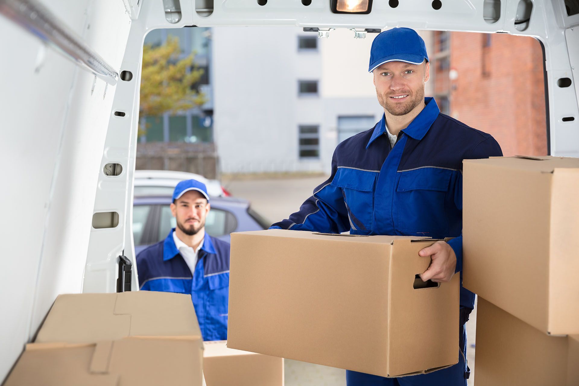 Cardboard boxes being unloaded from truck during professional furniture removals service.