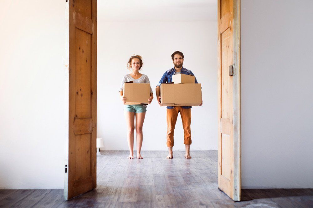 two people standing in a doorway holding a box