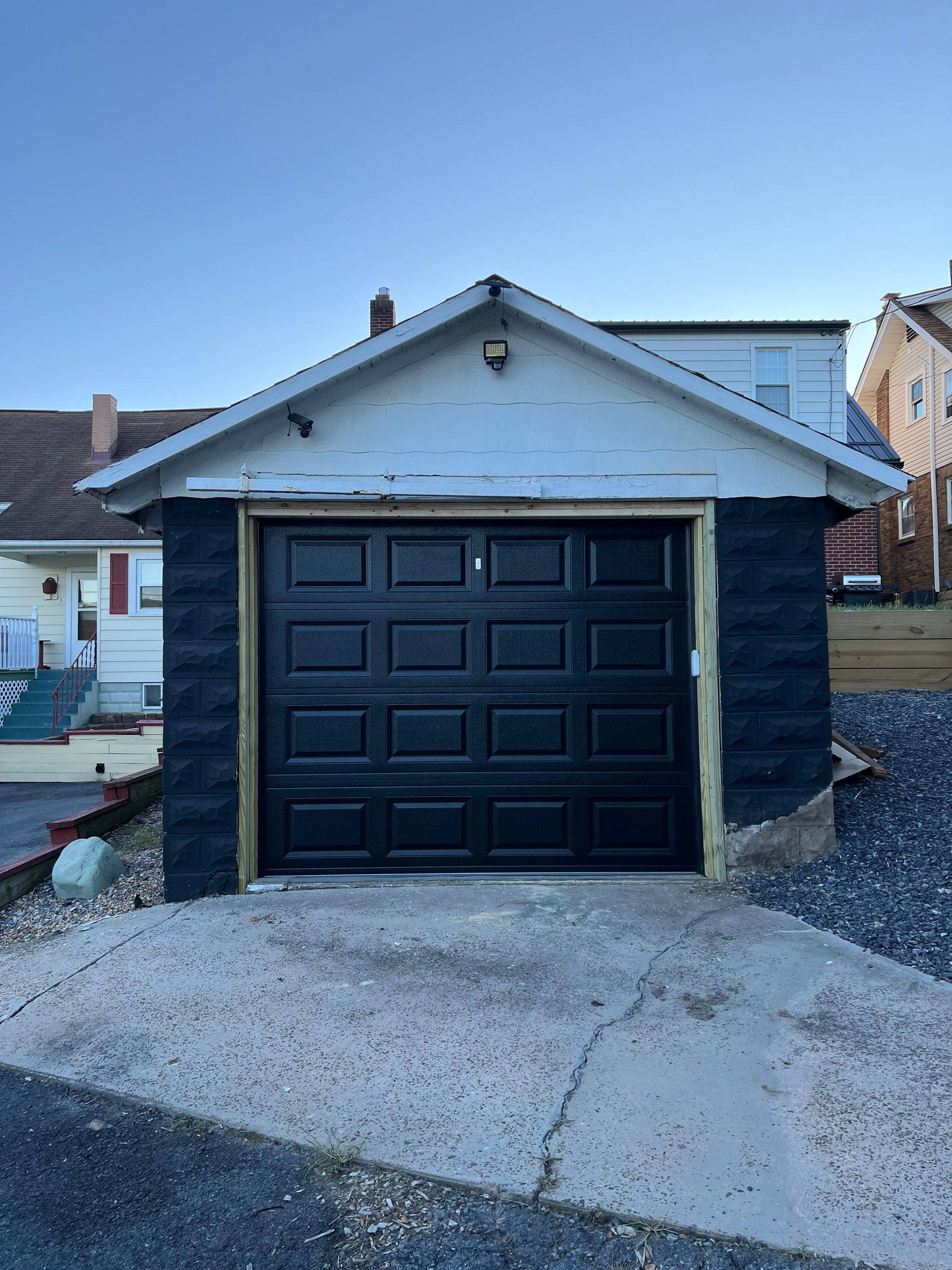 A black garage door is sitting in front of a house.