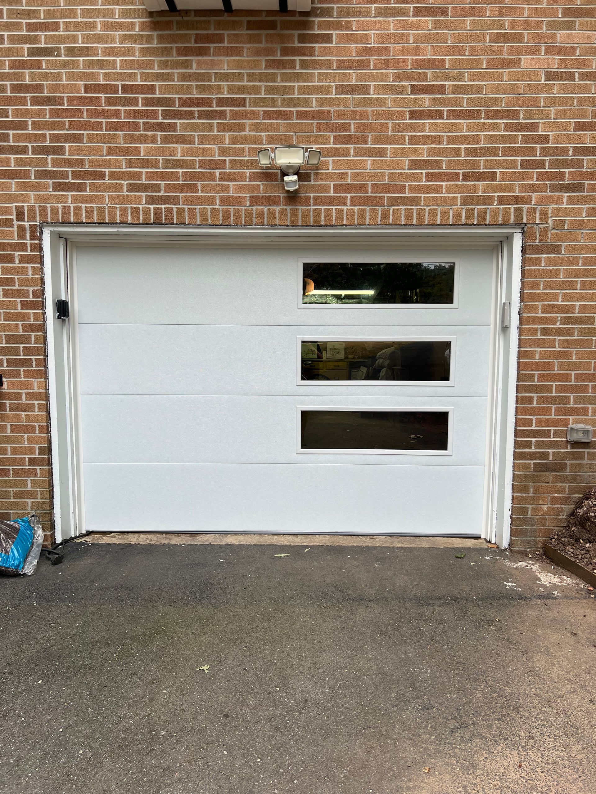 A white garage door is sitting in front of a brick building.