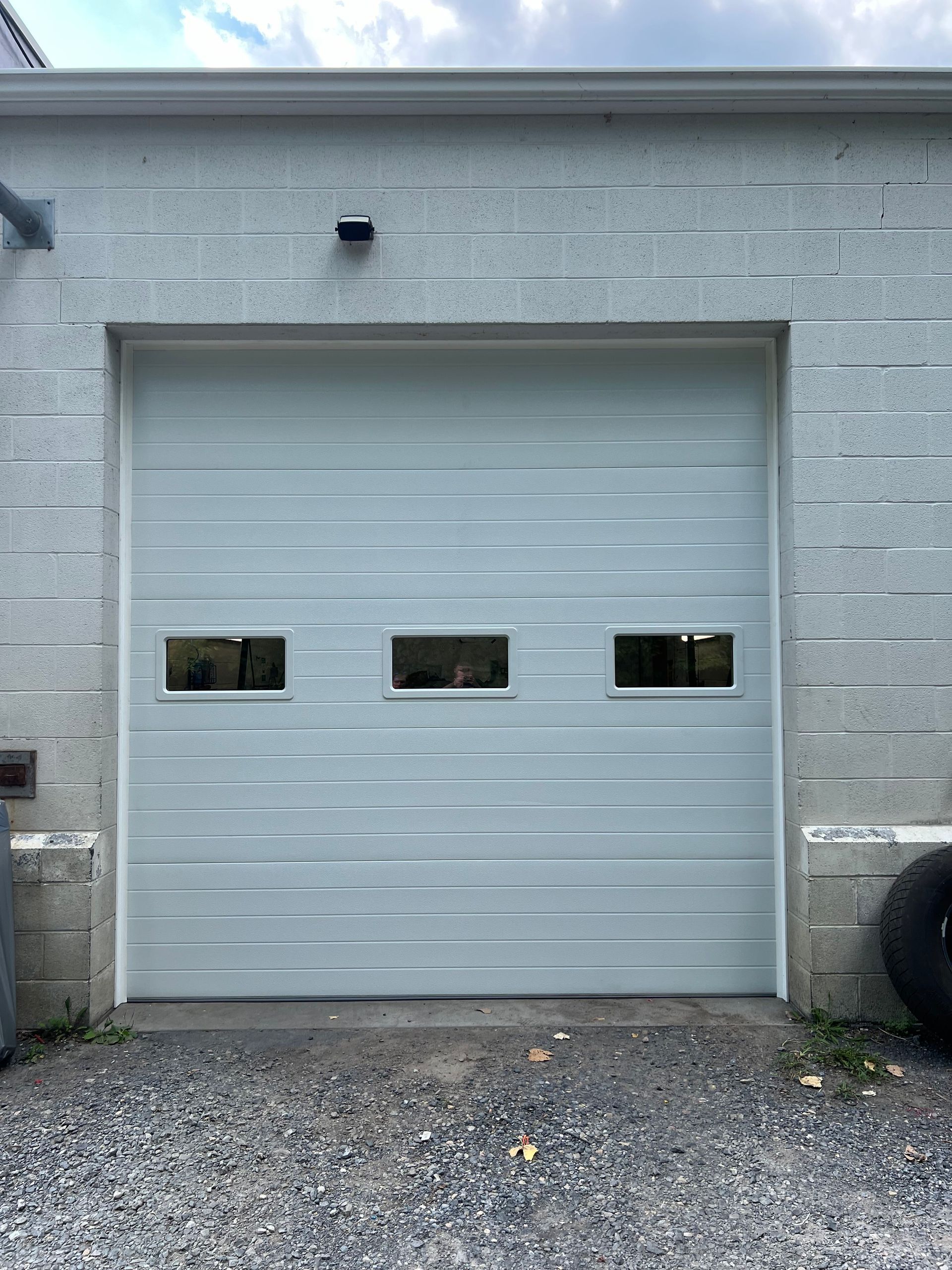 A white garage door with two windows on the side of a building.