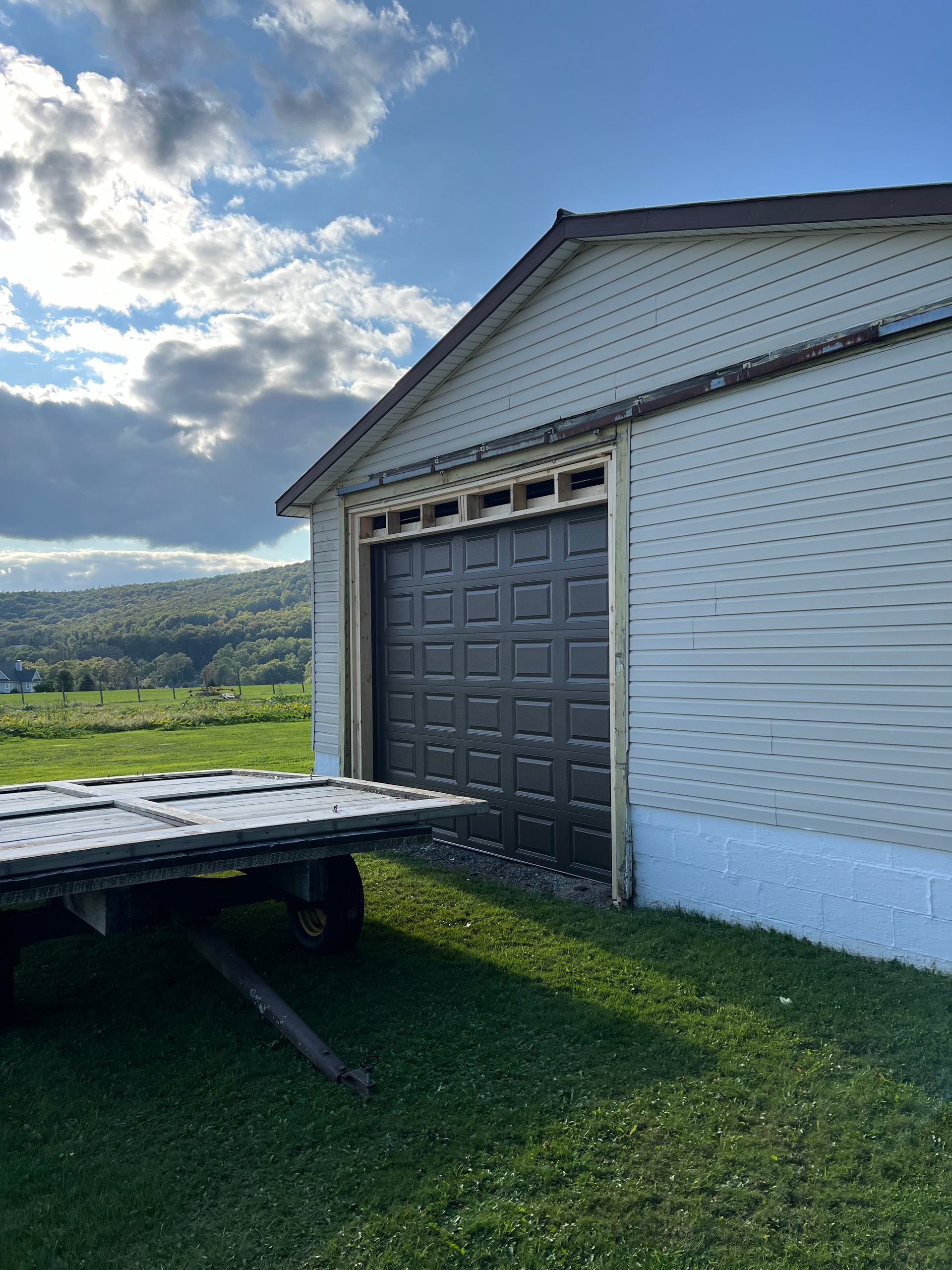 A trailer is parked in front of a garage door.