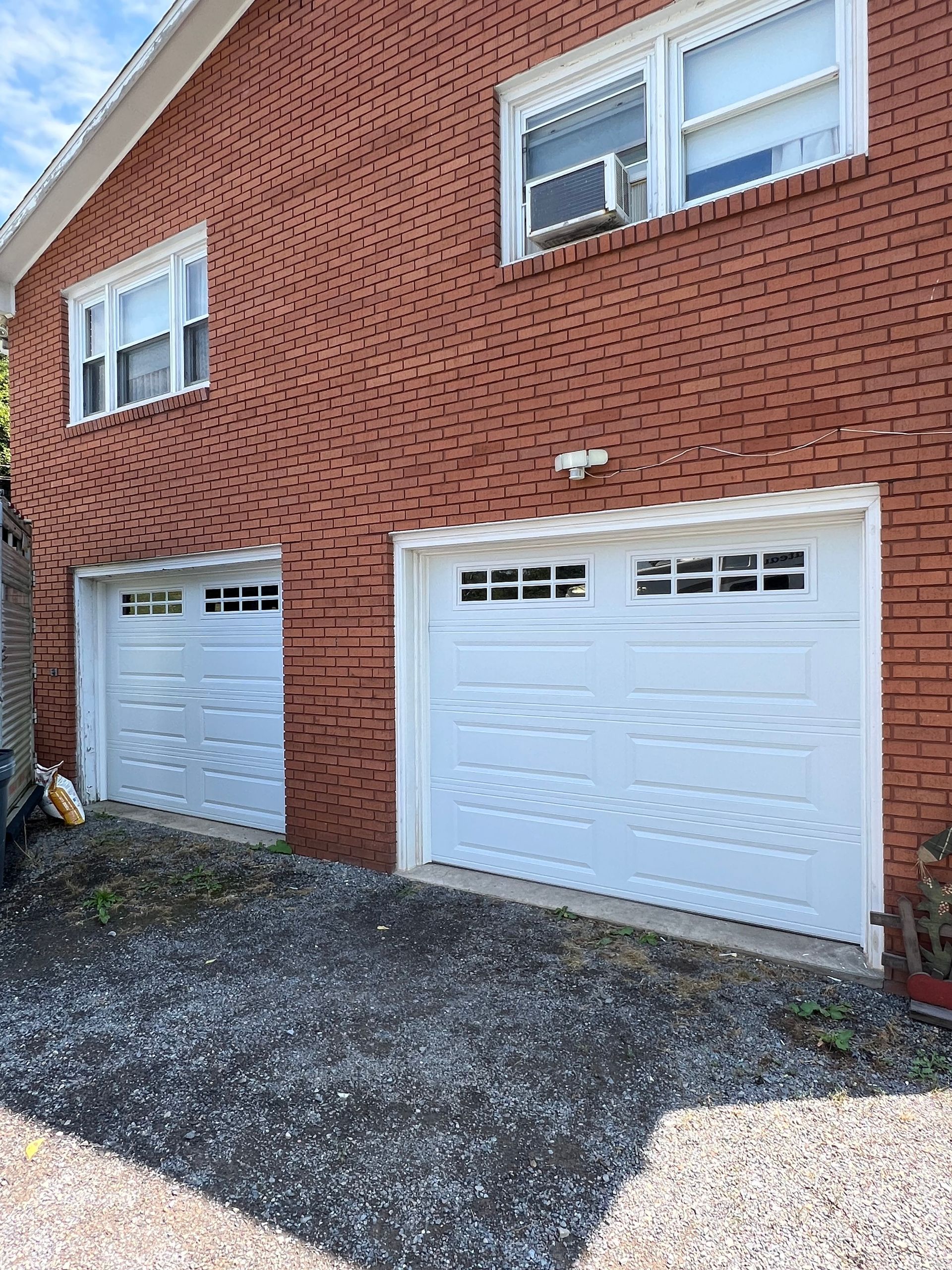 A red brick house with two white garage doors.
