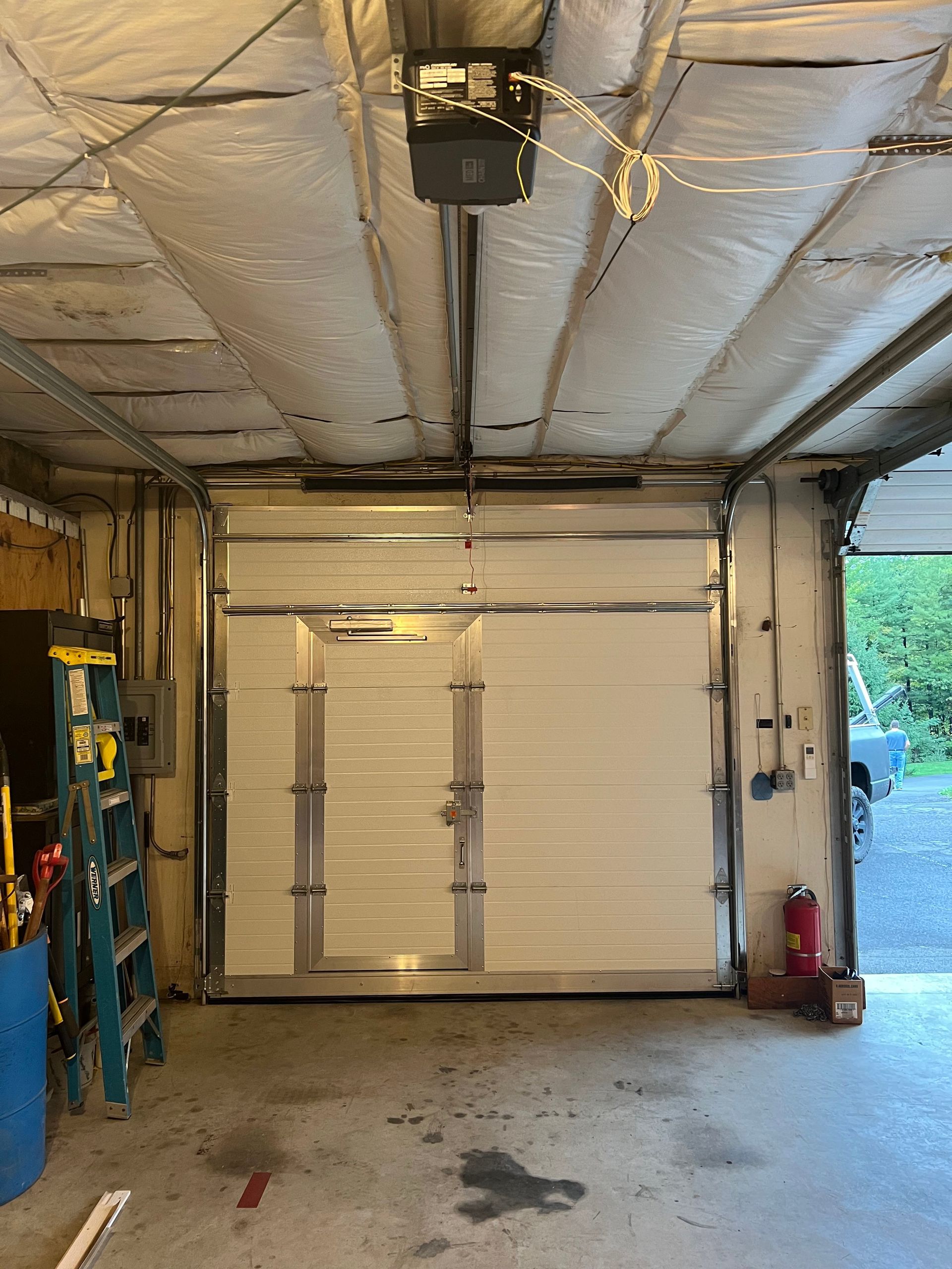 A garage with a garage door open and a ladder.