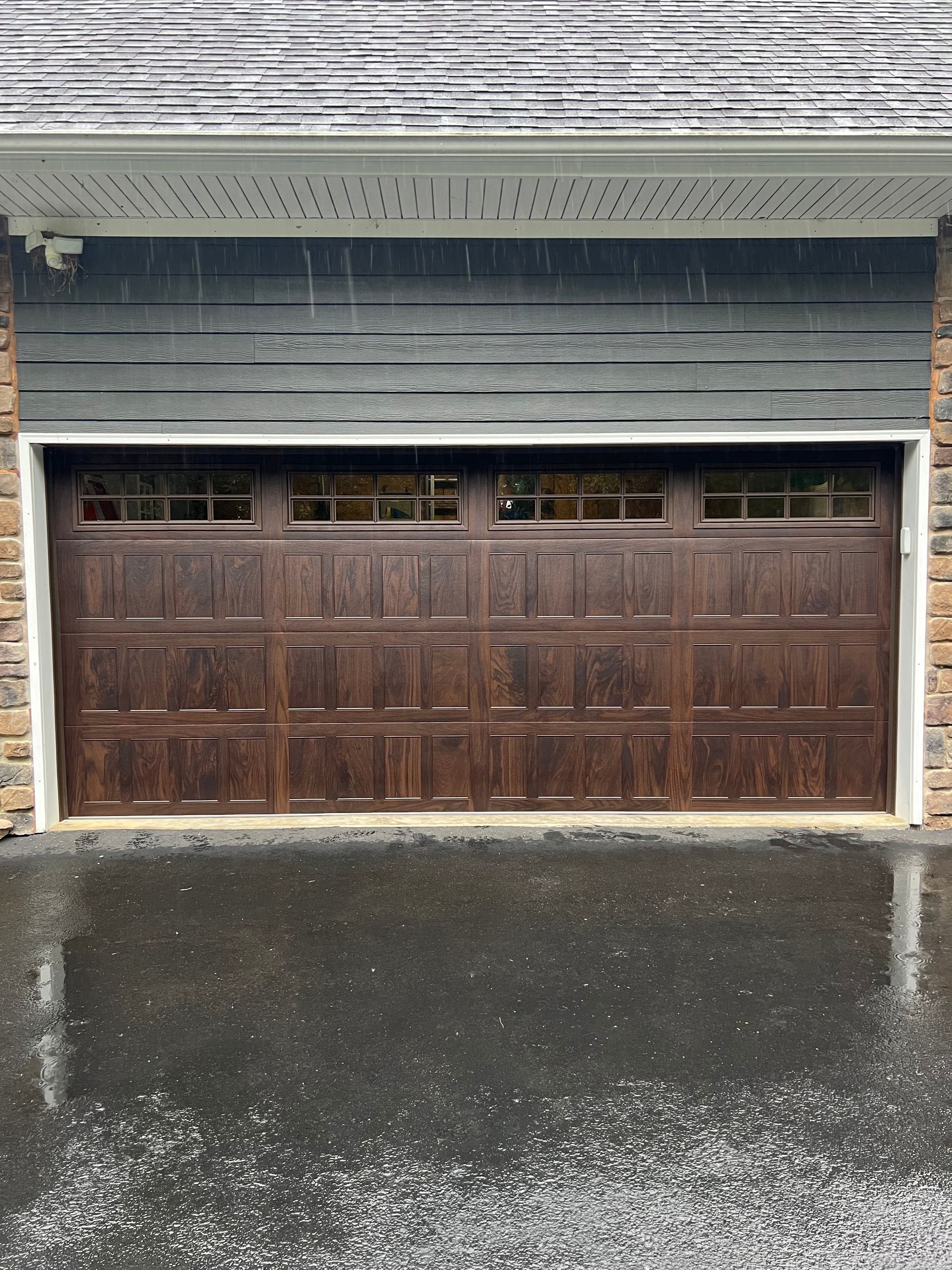 A brown garage door is sitting in front of a house.