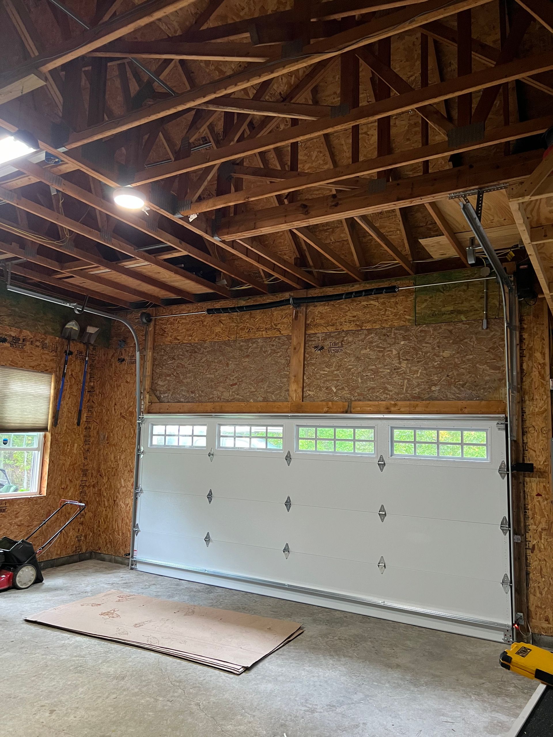 An empty garage with a garage door open and a mat on the floor.
