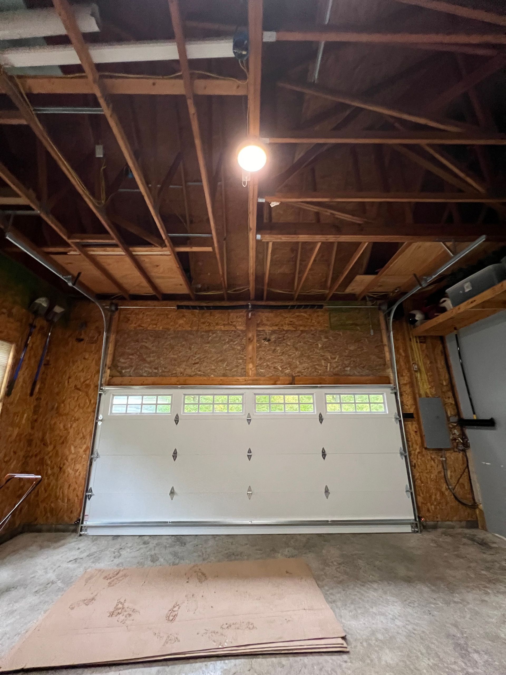 A garage with a garage door open and a light on the ceiling.