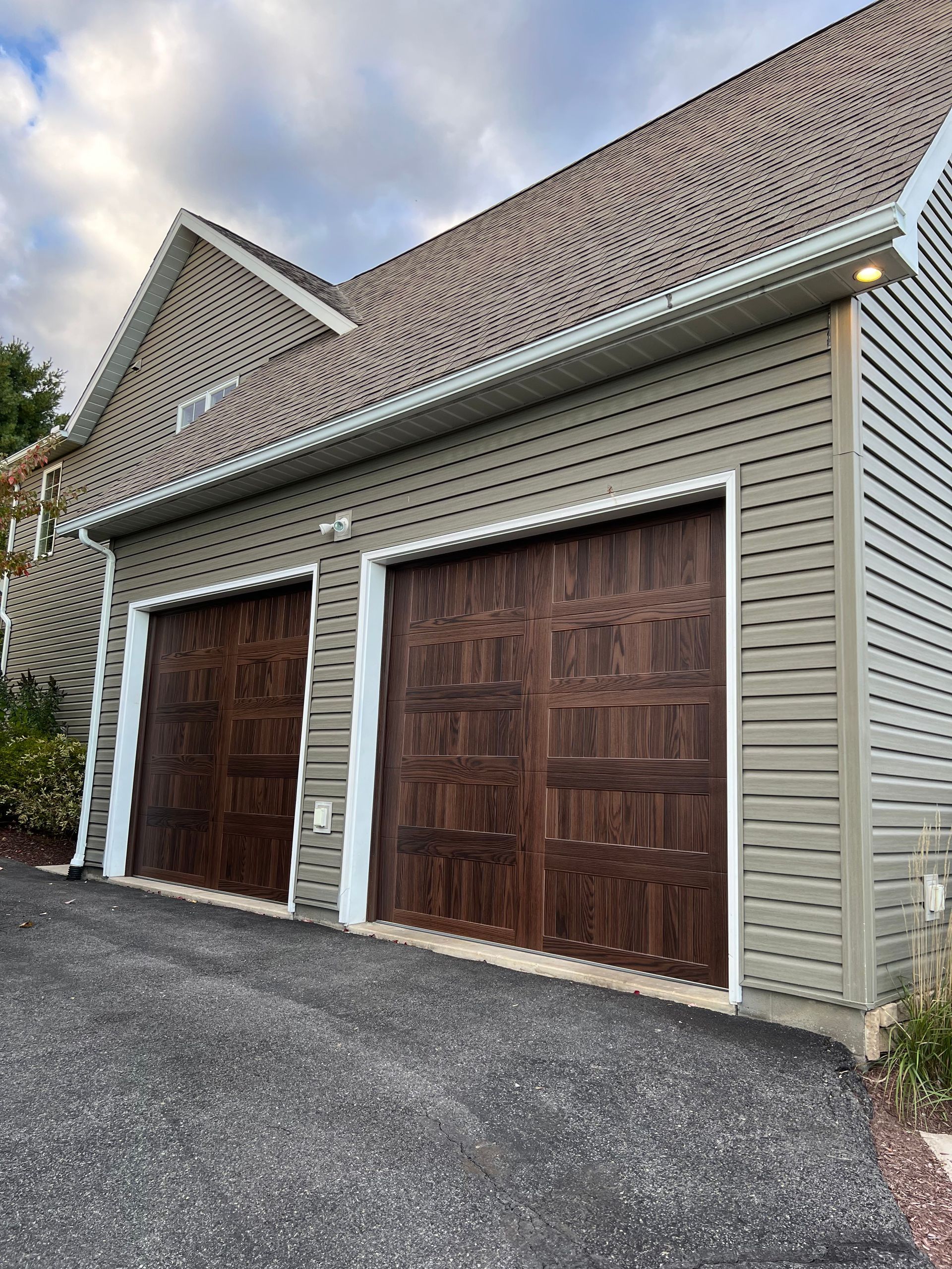 There are two garage doors on the side of a house.