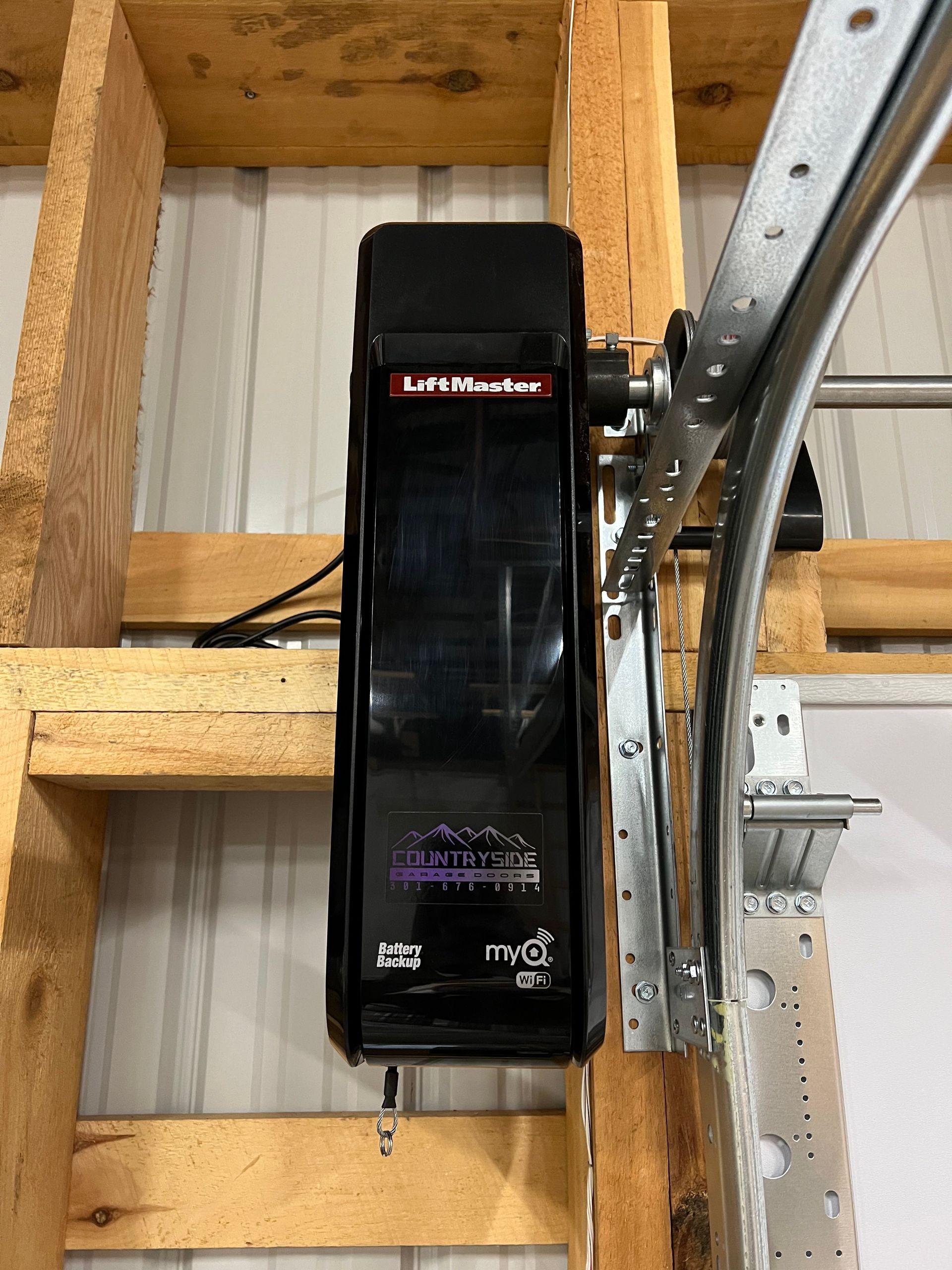 A garage door opener is sitting on top of a wooden shelf.