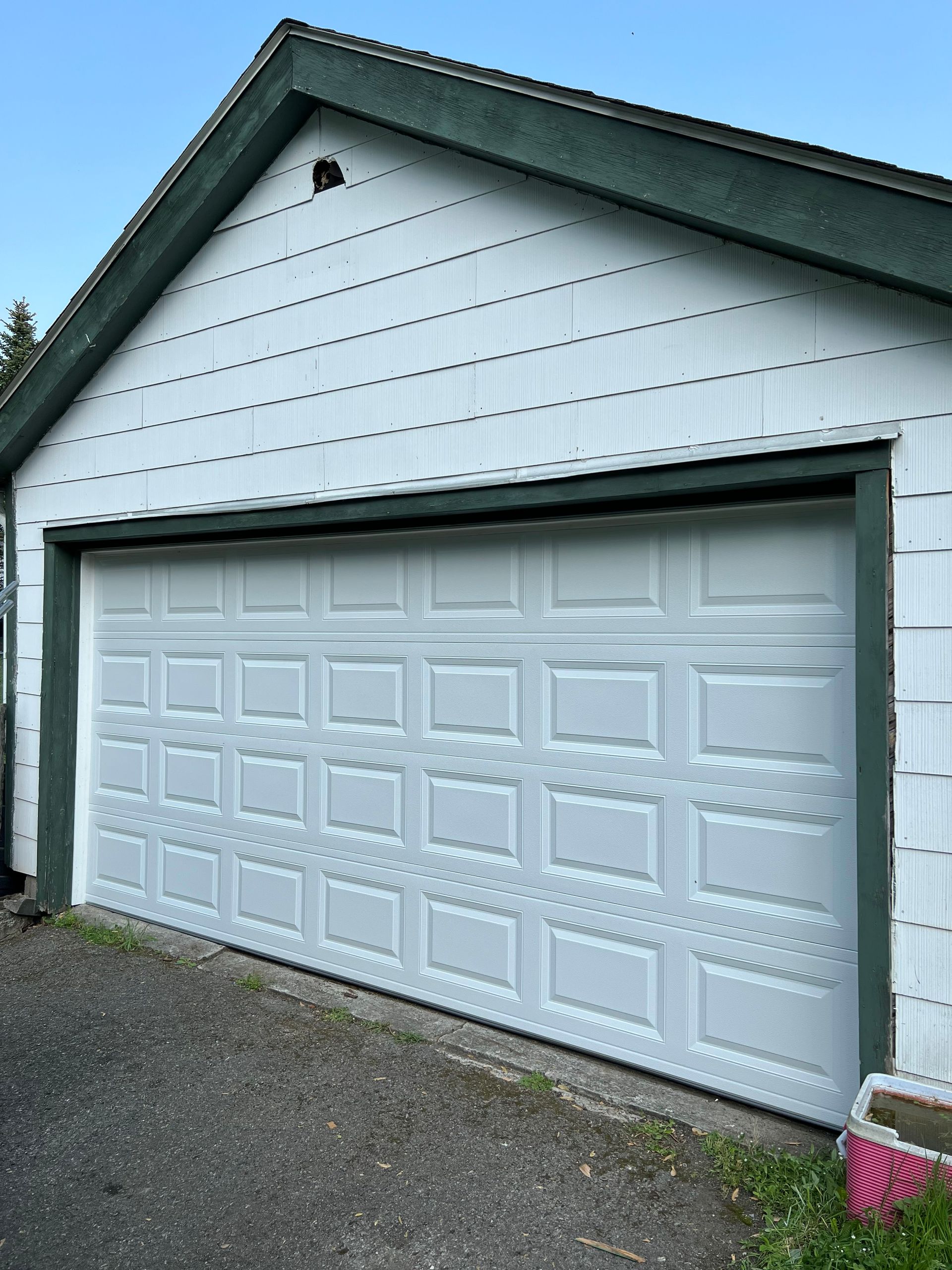 A white garage door with a green trim is open