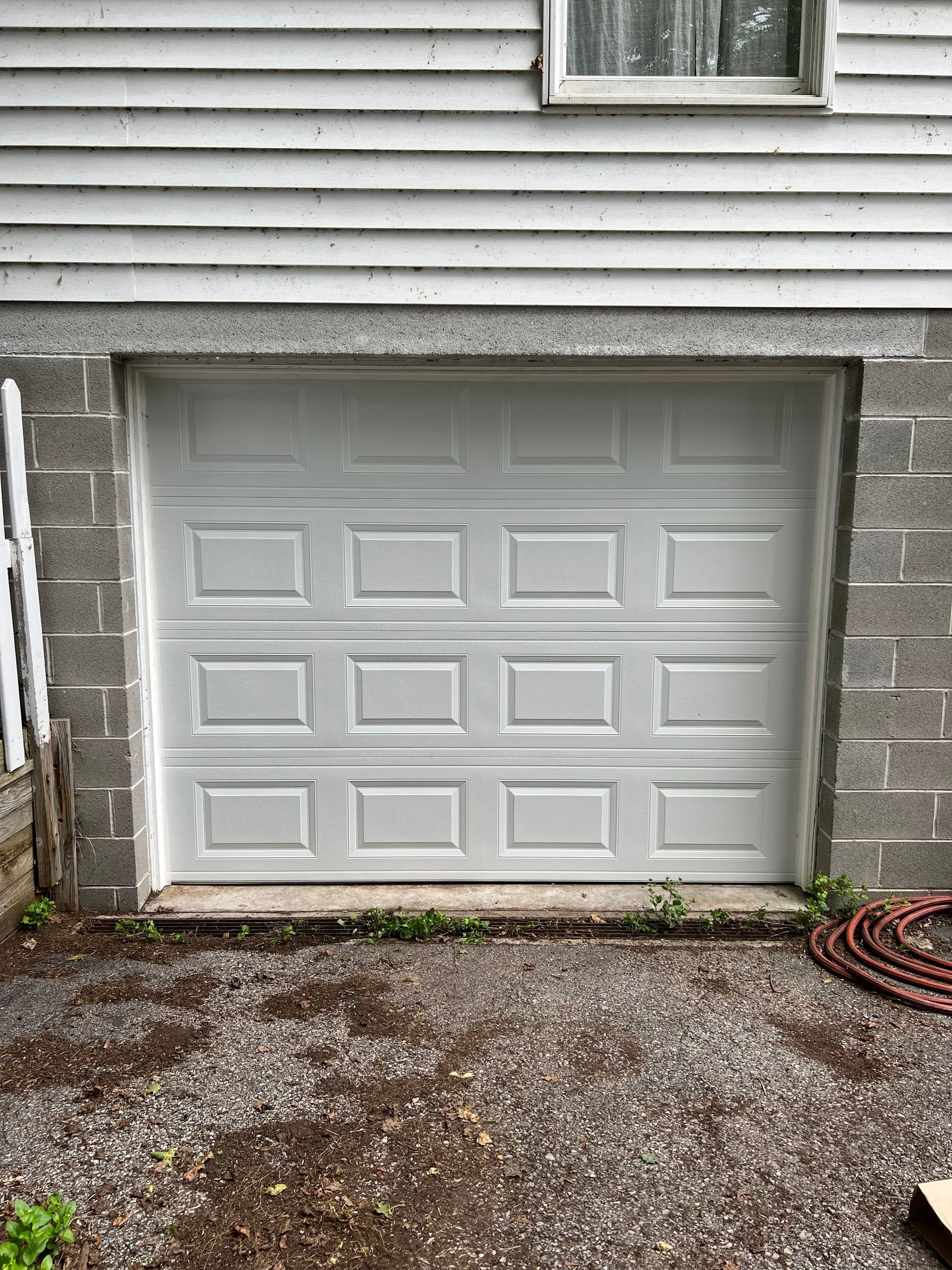 A white garage door is sitting on the side of a brick house.