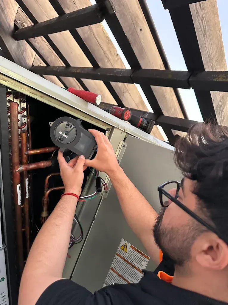 Person using a flashlight to inspect wiring inside a ceiling panel area