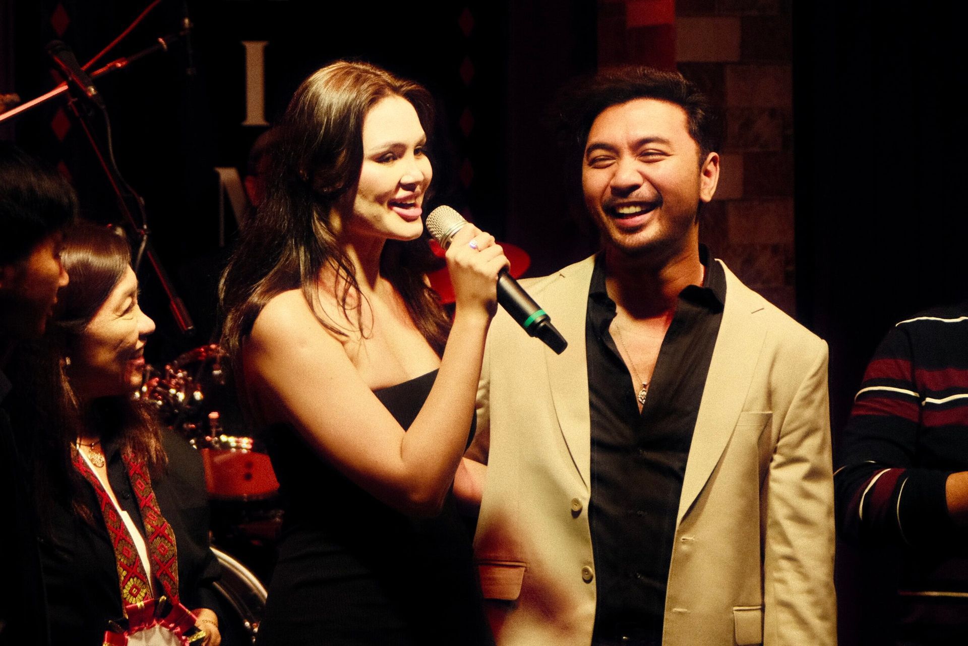 A woman singing into a microphone next to a man in a suit