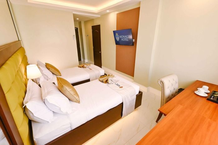 A hotel room with two beds , a desk and a television.