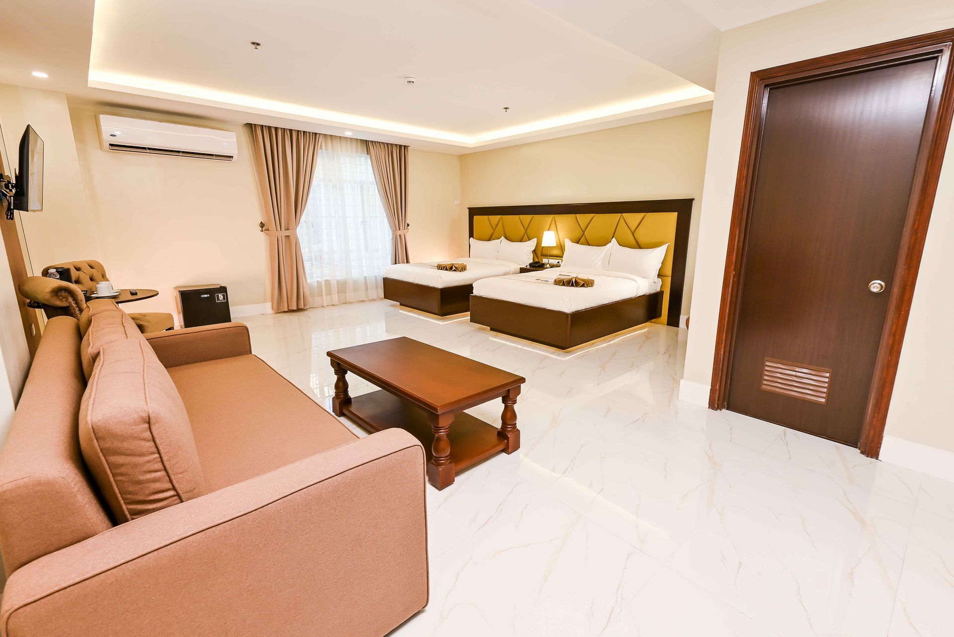 A hotel room with two beds , a couch , and a coffee table.