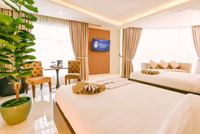 A hotel room with two beds , a couch , a table and a television.