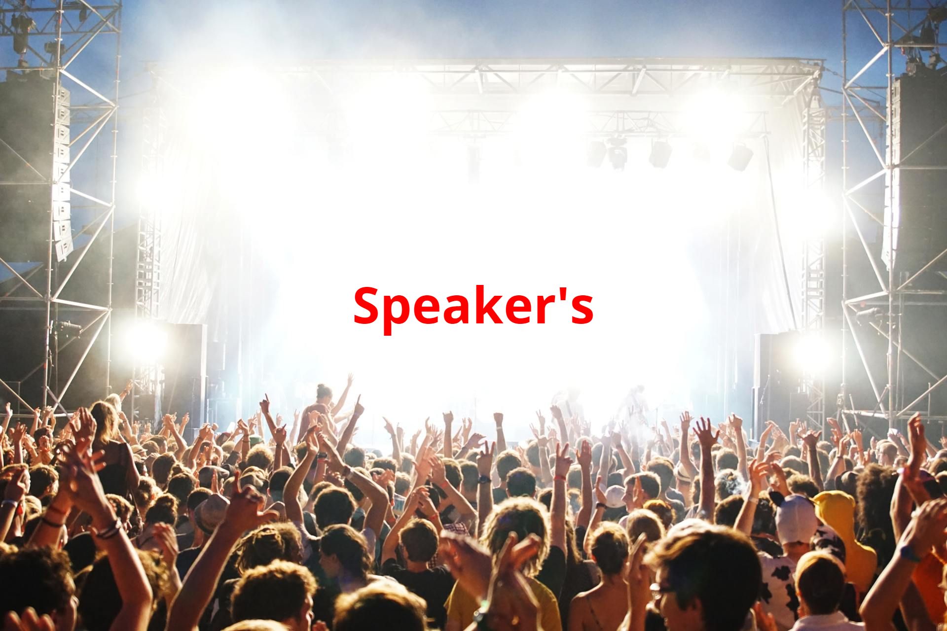 A large crowd with raised arms at a concert, stage lights shining bright, with