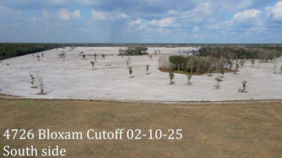 Aerial view of a cleared, sandy field with scattered trees and vegetation, labeled 