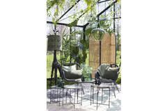 Serre met stoelen, tafel en planten. Groene en beige tinten, natuurlijk licht.