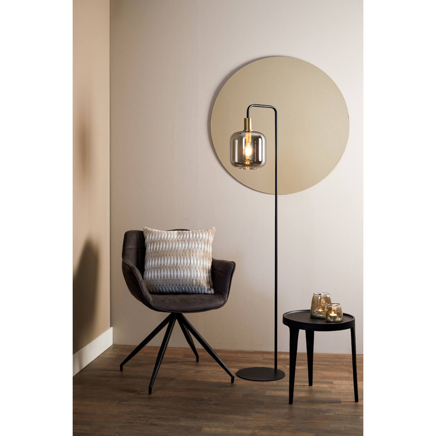 Een modern interieur met een staande lamp, stoel, bijzettafel en een ronde spiegel aan de muur.