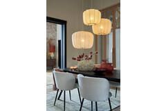 Eetkamer met drie hangende papieren lantaarns boven een donkere tafel en lichtgrijze stoelen.