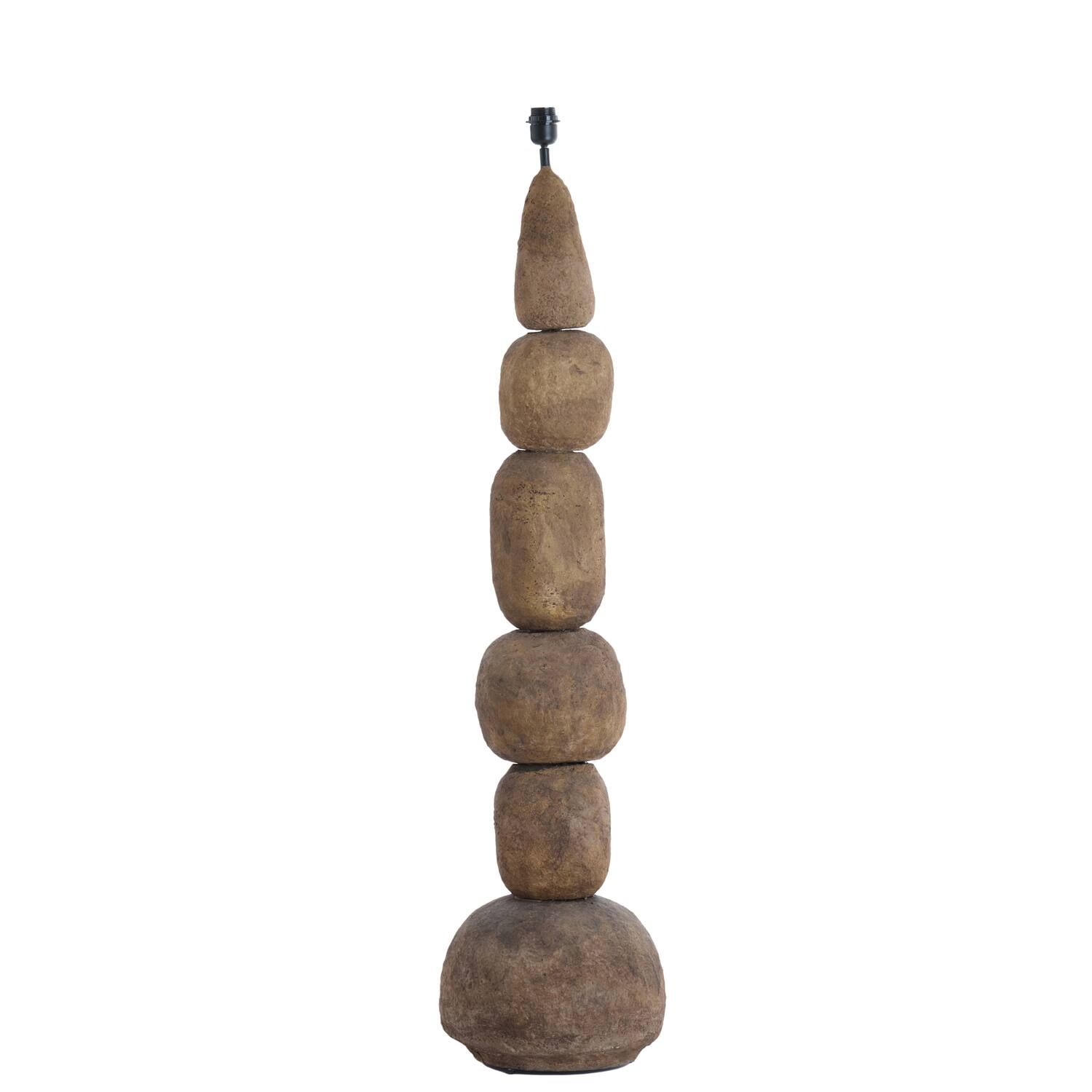 Houten vloerlamp met een ontwerp van gestapelde stenen, naast een donkere kast met een geweven front.