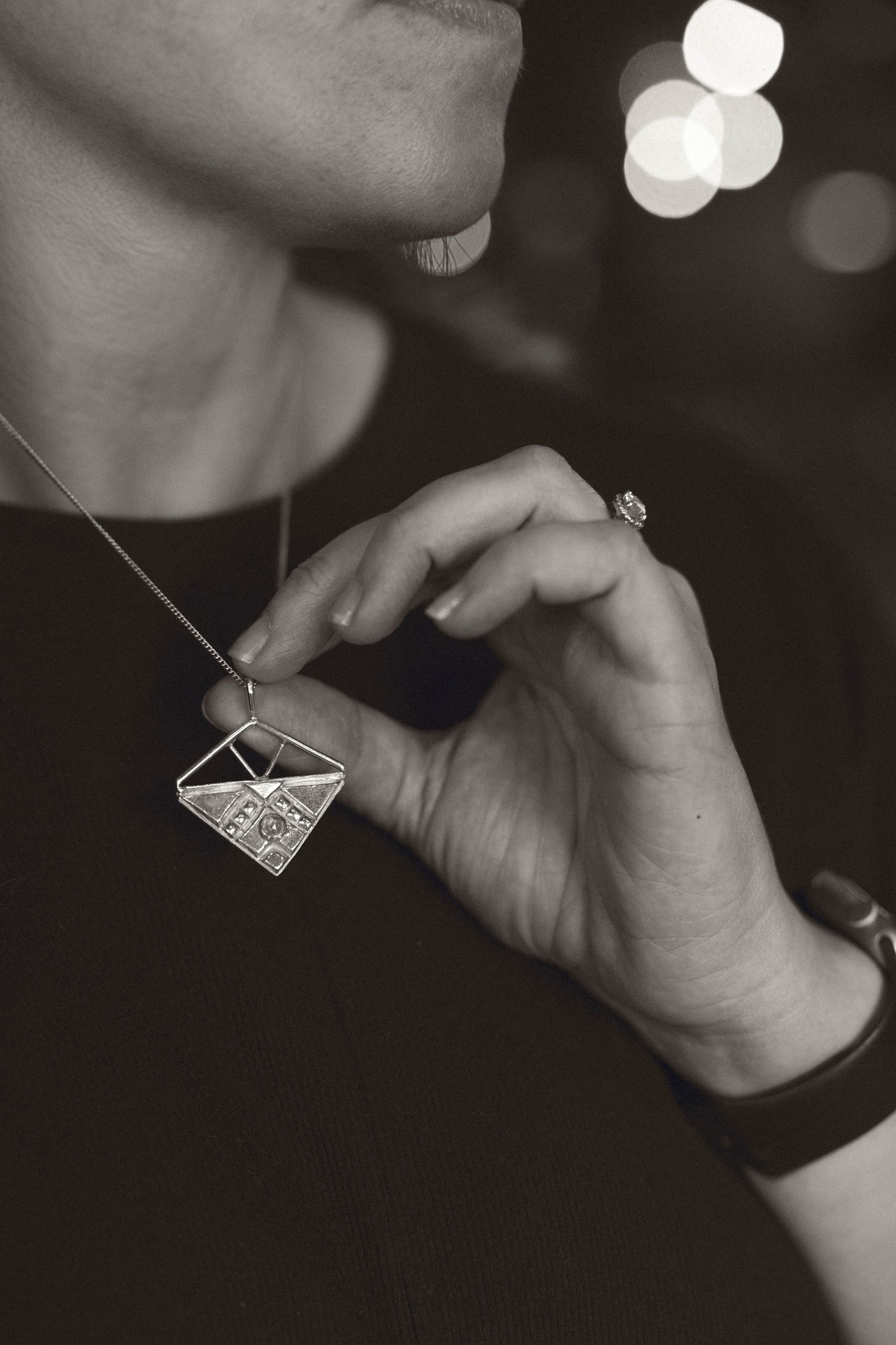 Silver geometric pendant necklace with small clear gems on gray backdrop. Wild Sunflower Silver Handmade Jewelry